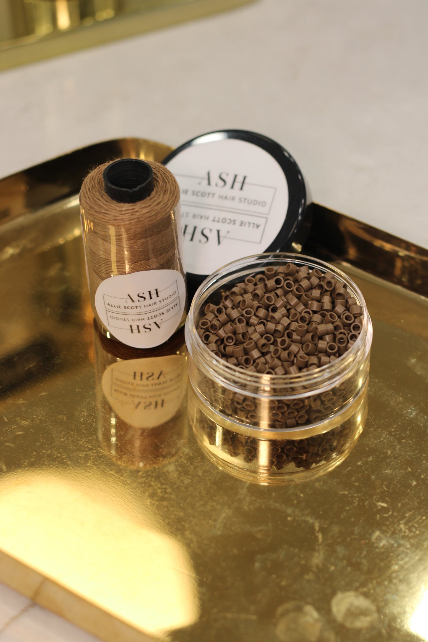 Two small containers with gold lids on a reflective surface