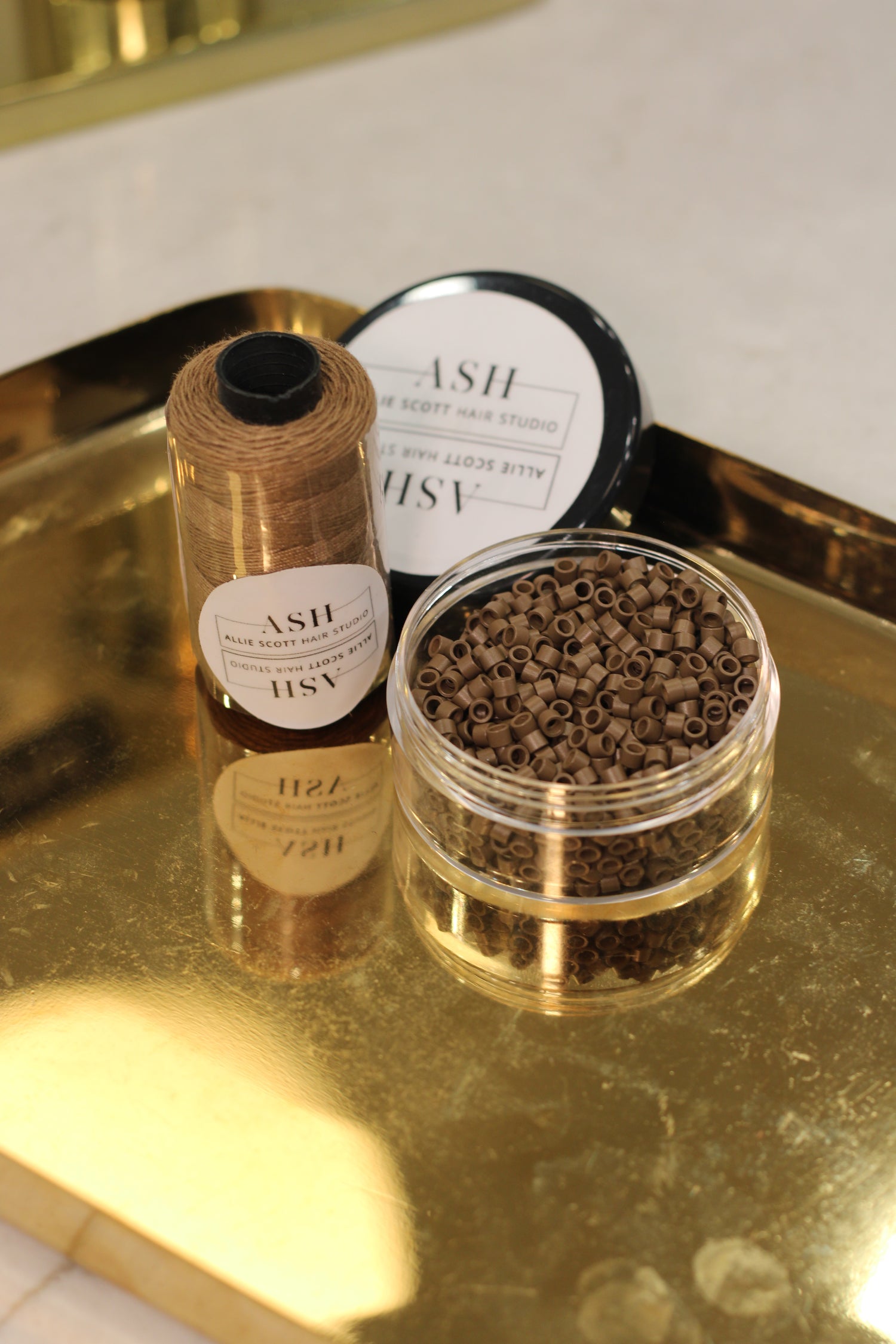 Two small containers with gold lids on a reflective surface